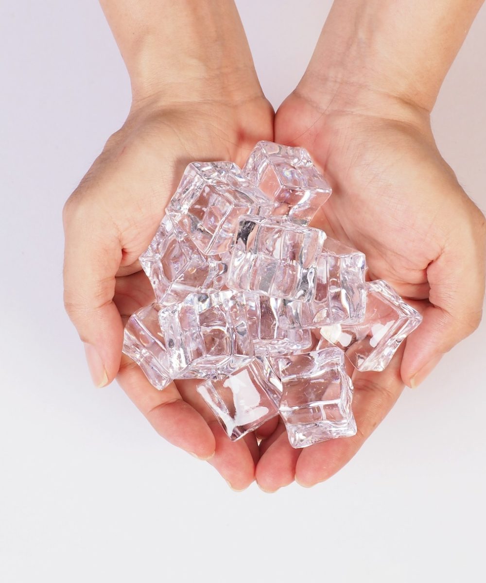 hands is holdine ice cubes isolated on white background.